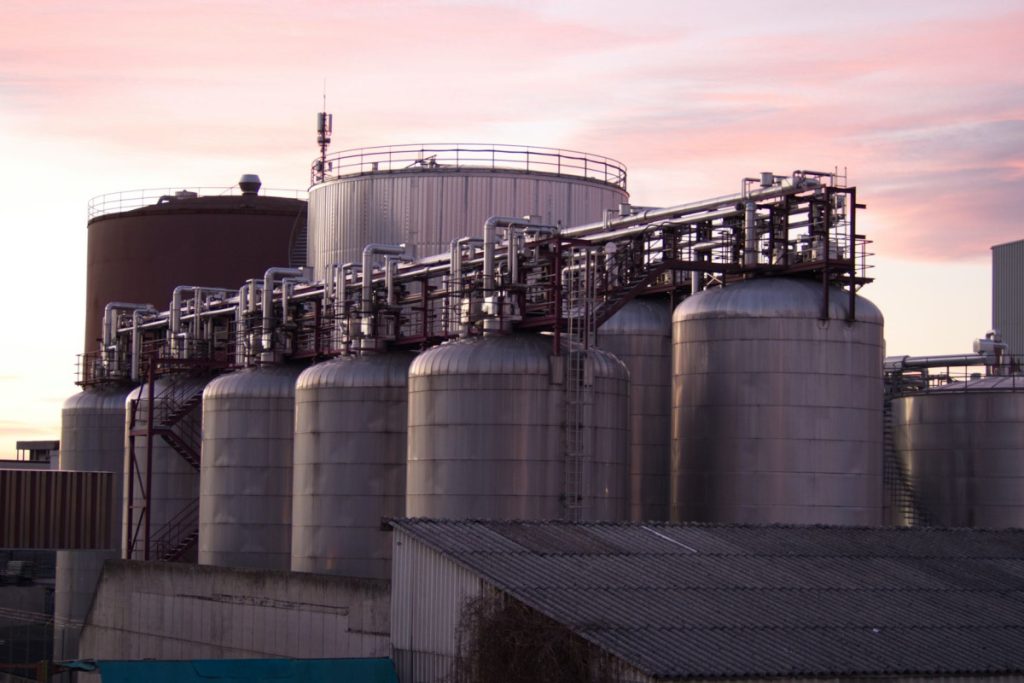A refinery with large stainless steel storage tanks during sunset, showcasing industrial infrastructure.