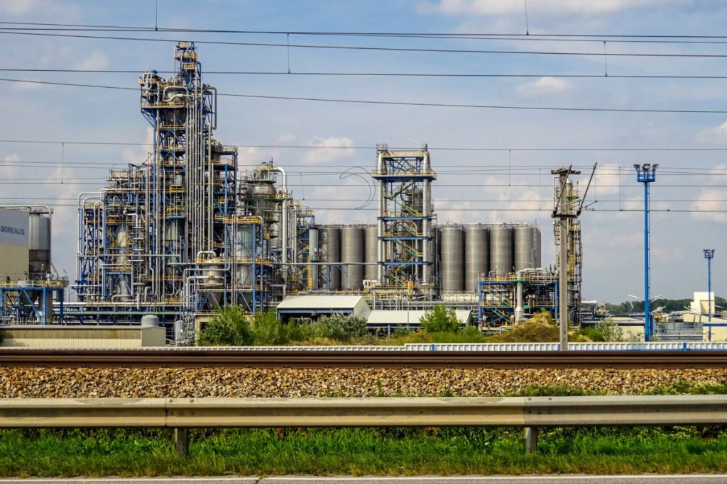 Image of a large chemical factory in Schwechat, Austria, showcasing industrial pipes and machinery.