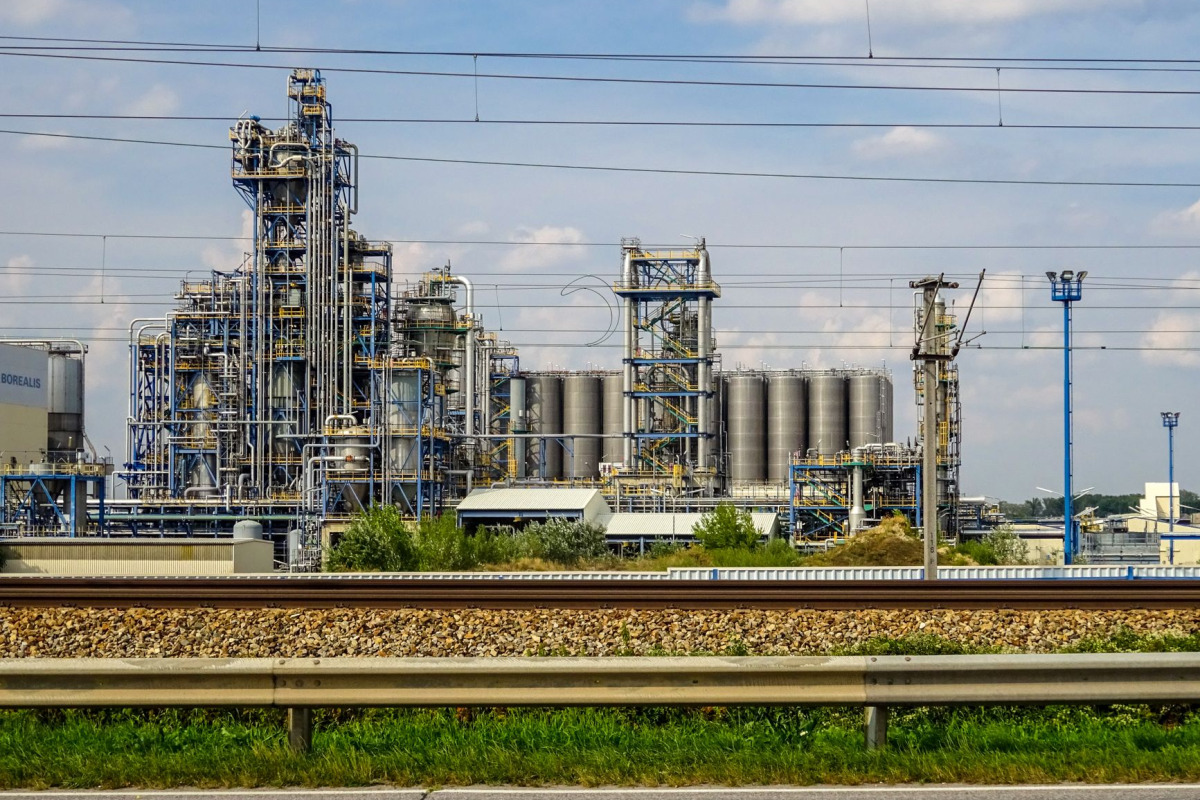 Image of a large chemical factory in Schwechat, Austria, showcasing industrial pipes and machinery.