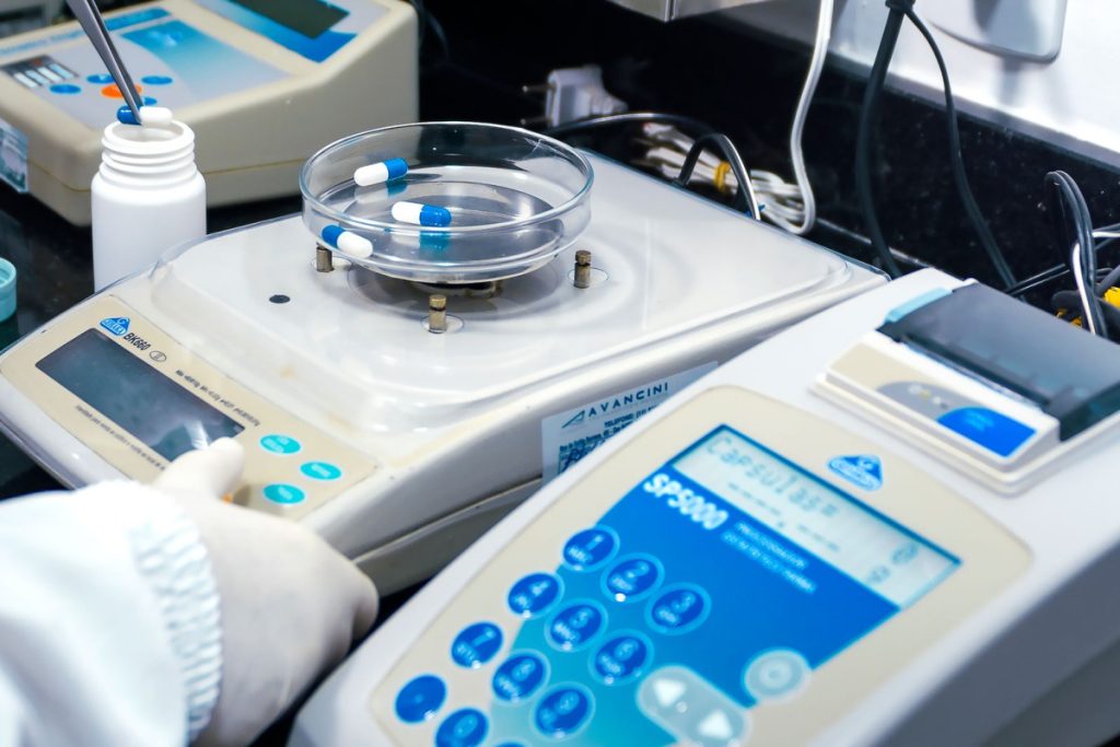 Close-up of laboratory equipment with capsules, capturing pharmaceutical analysis.